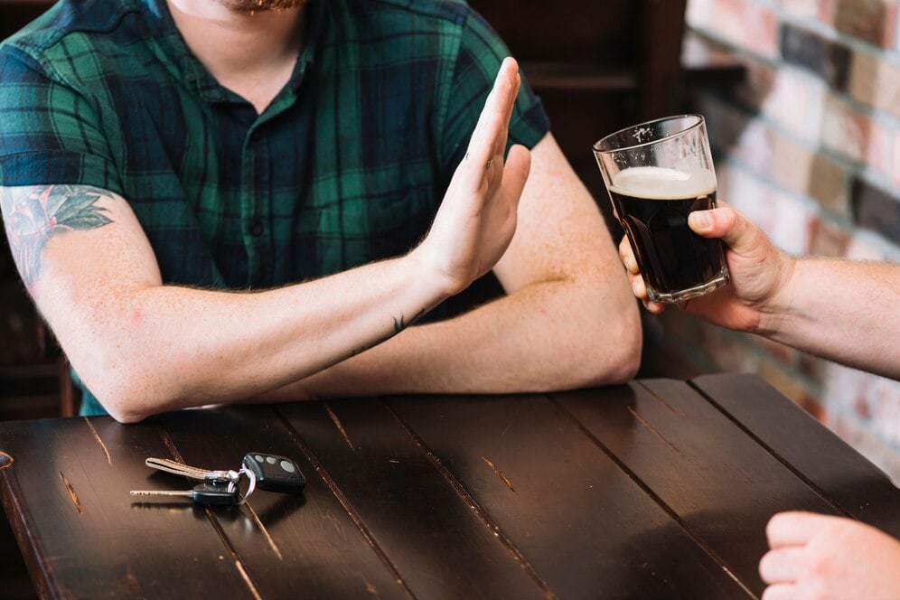 man hold hand up to drink being offered