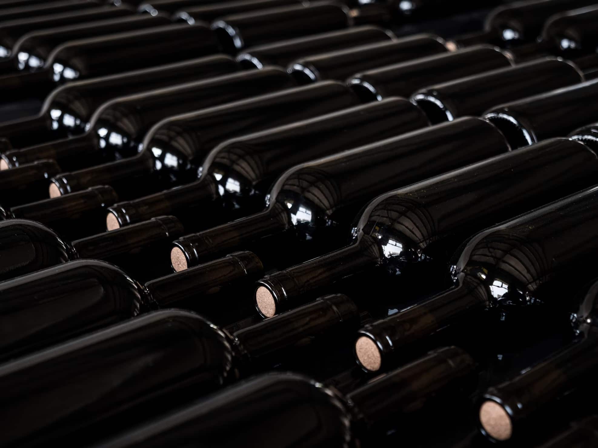 A row of black bottles lined up with brown corks