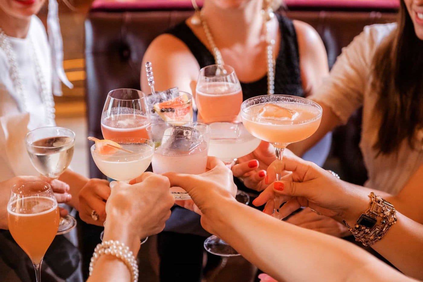 Group of women cheering with different pink and clear drinks