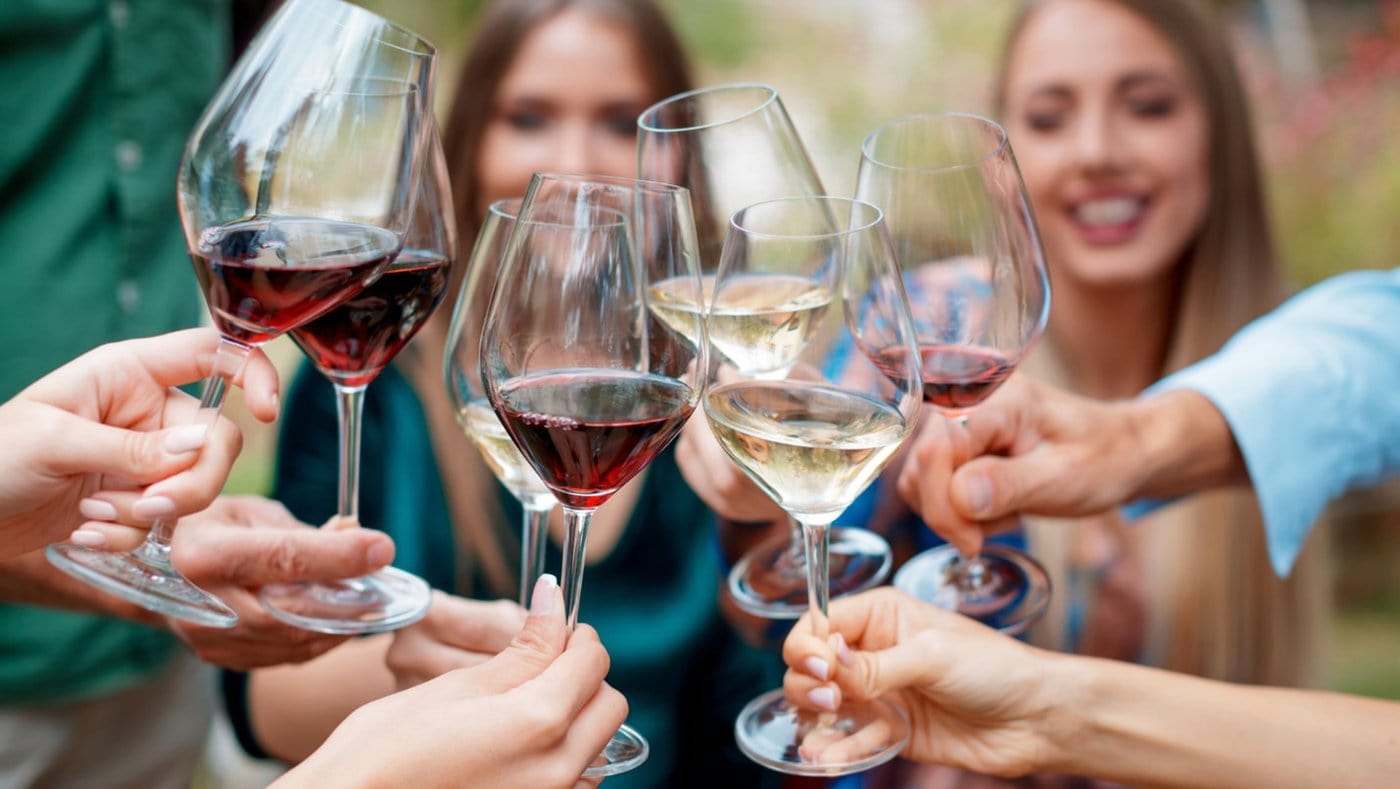 Seven people cheers together with wine glasses.