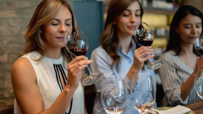 Three women in business attire at a wine tasting.