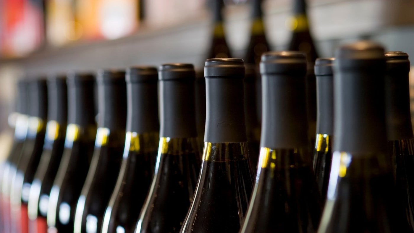 A row of unlabeled wine in green glass bottles.